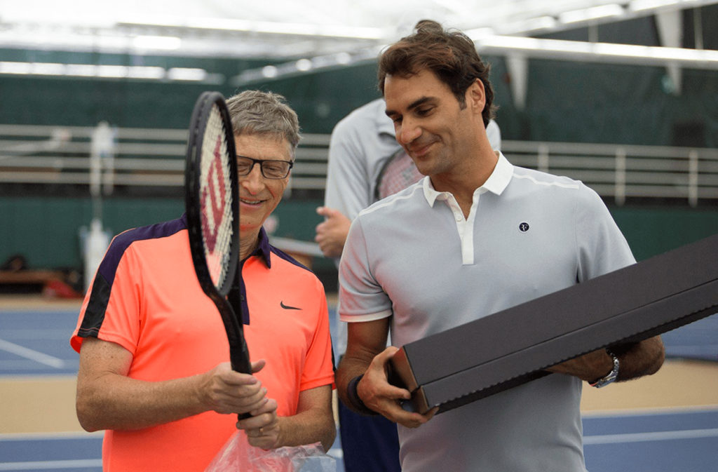 Bill Gates and Roger Federer looking at a tennis racket.