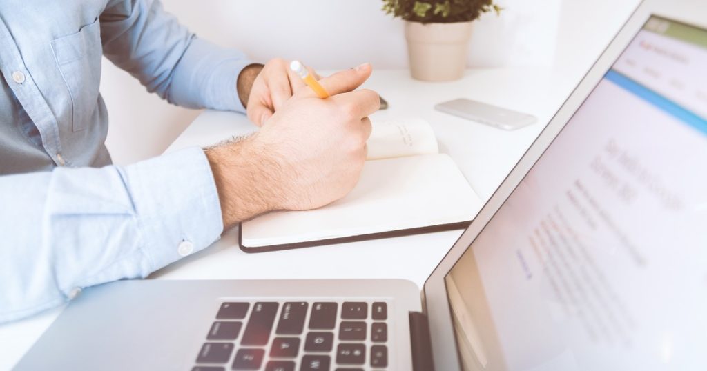 Person working in front of laptop and book.